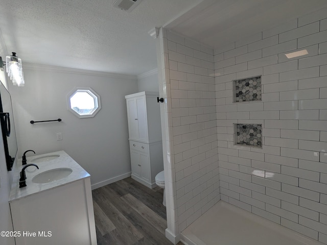 full bath with crown molding, toilet, a sink, a textured ceiling, and wood finished floors