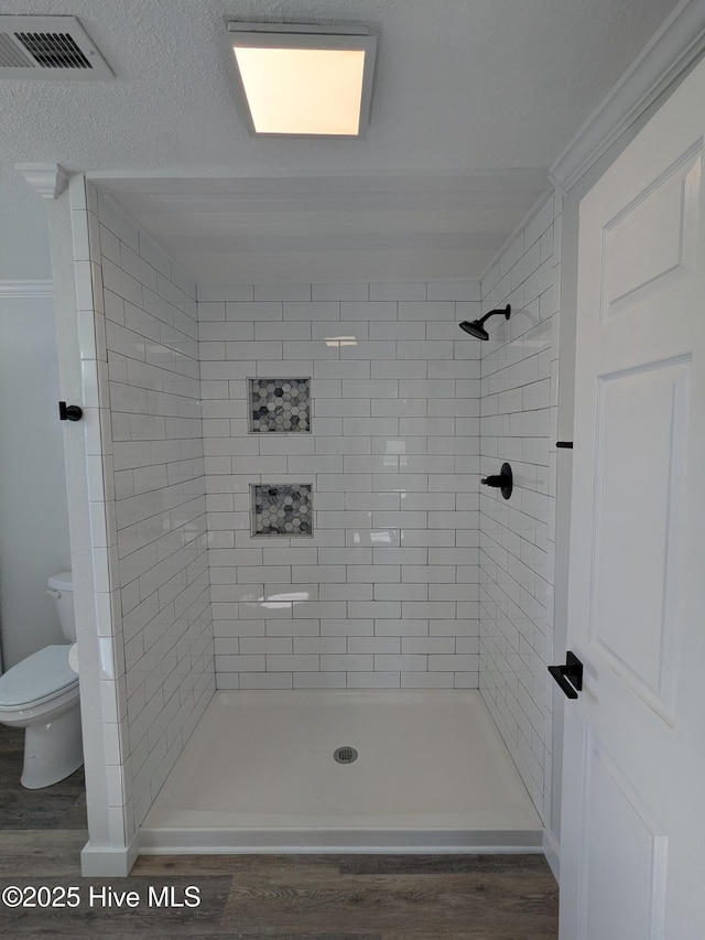 bathroom featuring toilet, a shower stall, visible vents, and wood finished floors