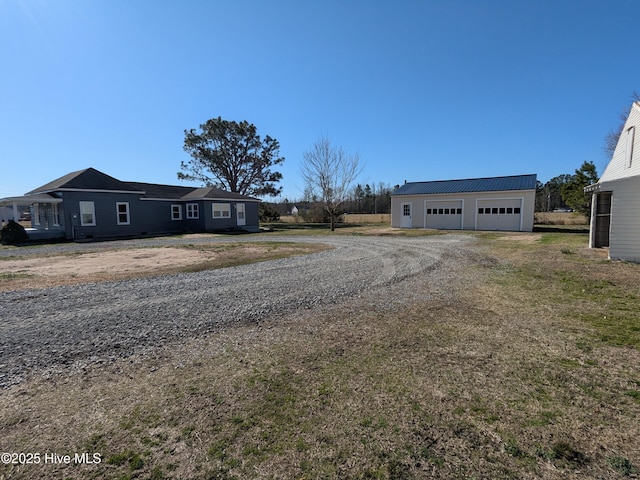 view of front of home featuring a detached garage, metal roof, and an outbuilding