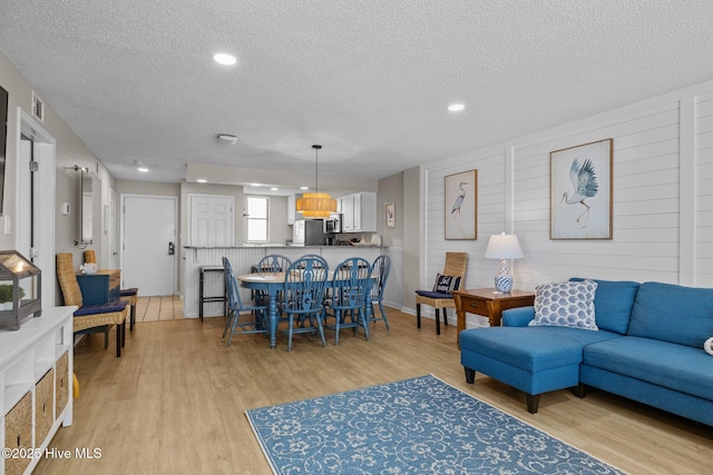 living room featuring a textured ceiling, light wood finished floors, and recessed lighting