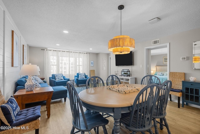 dining area featuring a textured ceiling, light wood-style floors, and recessed lighting
