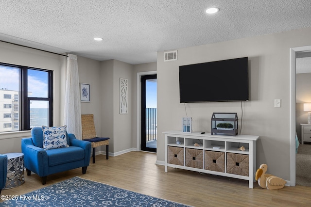living room with wood finished floors, a textured ceiling, baseboards, and recessed lighting