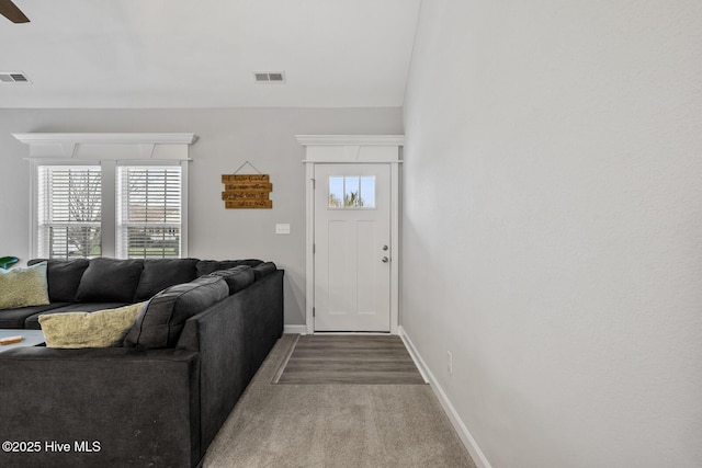 living room with baseboards, visible vents, and a ceiling fan