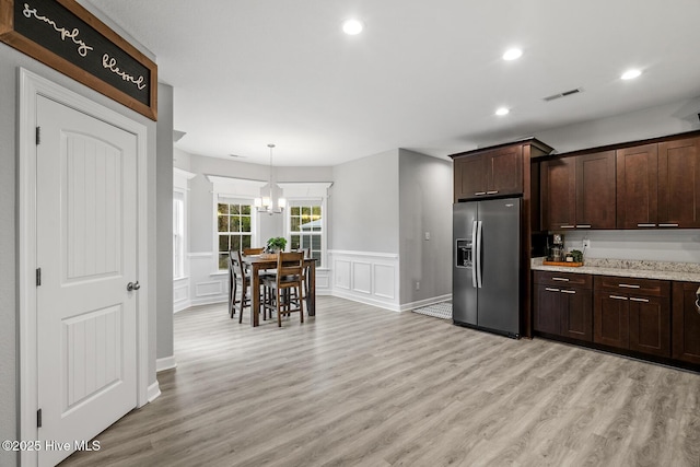 kitchen featuring light wood-style floors, visible vents, dark brown cabinetry, and stainless steel fridge with ice dispenser