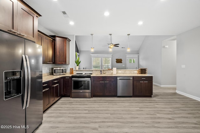 kitchen featuring a peninsula, stainless steel appliances, a sink, and lofted ceiling