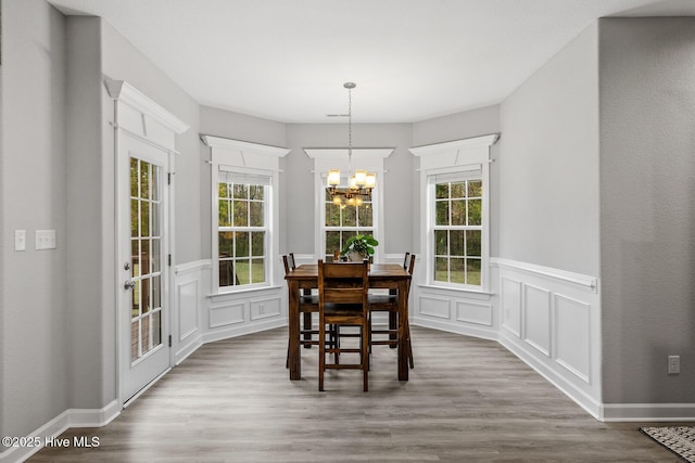 dining area with wood finished floors, a wealth of natural light, and a notable chandelier