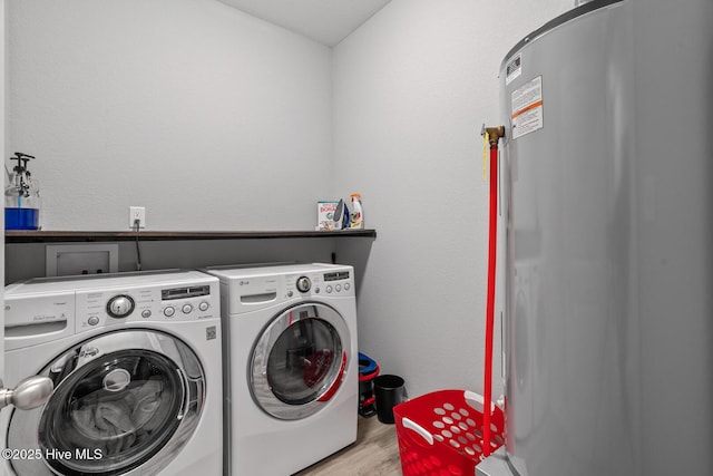 laundry room featuring water heater, laundry area, separate washer and dryer, and wood finished floors