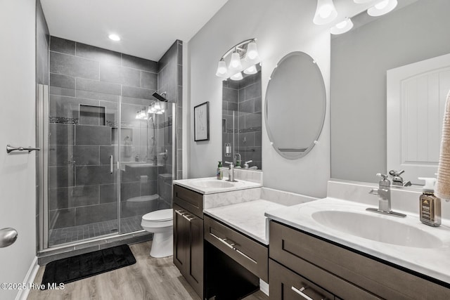 bathroom with vanity, a shower stall, toilet, and wood finished floors