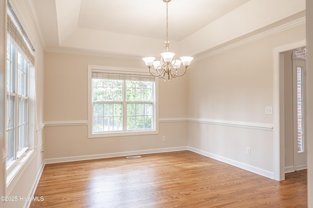 unfurnished room with an inviting chandelier, light wood finished floors, a raised ceiling, baseboards, and visible vents