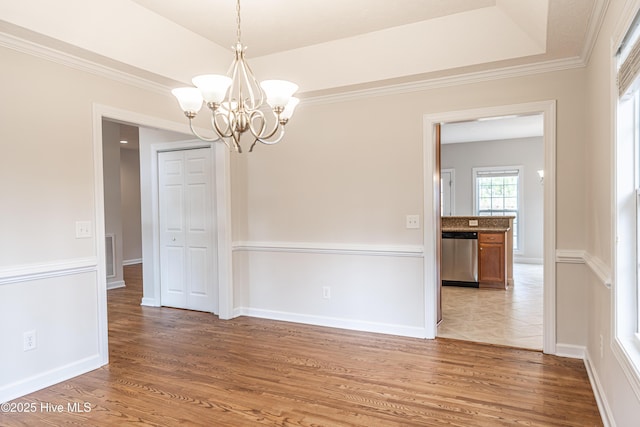 unfurnished dining area featuring light wood-type flooring, ornamental molding, baseboards, and a notable chandelier