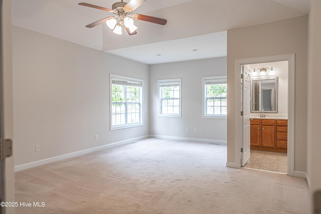 unfurnished bedroom featuring baseboards, a sink, light carpet, and ensuite bathroom