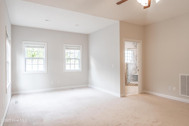 carpeted spare room featuring baseboards, a ceiling fan, and visible vents