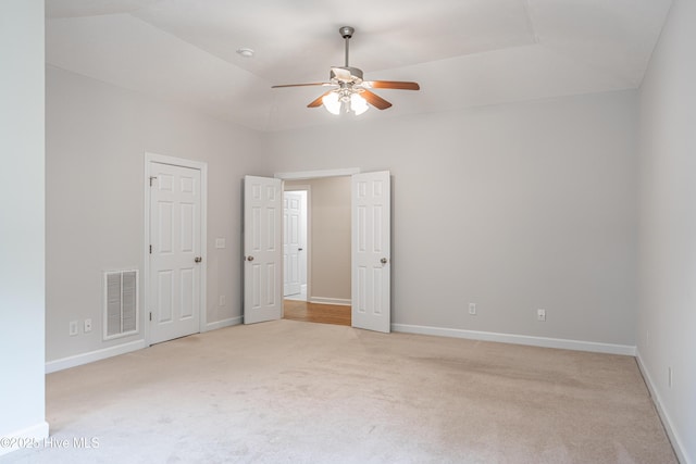 unfurnished bedroom featuring visible vents, baseboards, lofted ceiling, and light colored carpet