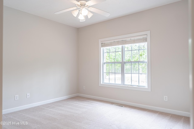 empty room with baseboards, a ceiling fan, visible vents, and light colored carpet