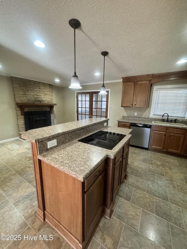 kitchen featuring a stone fireplace, black electric cooktop, a sink, dishwasher, and pendant lighting