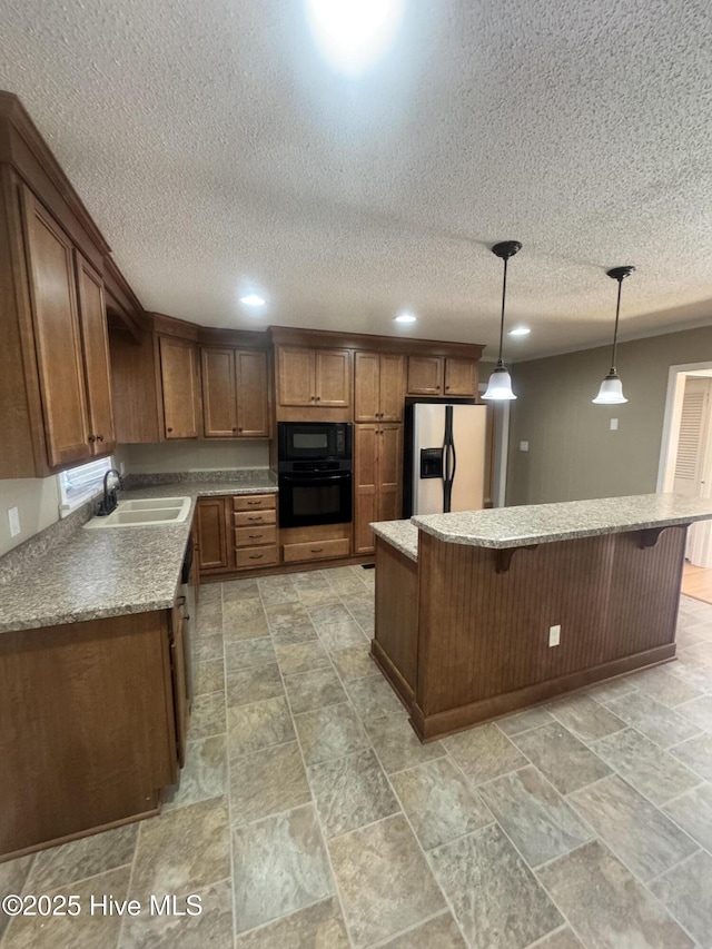 kitchen with a breakfast bar, a kitchen island, a sink, black appliances, and pendant lighting