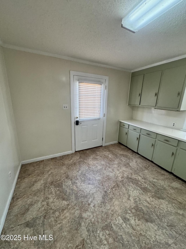 kitchen featuring light countertops, green cabinets, ornamental molding, a textured ceiling, and baseboards