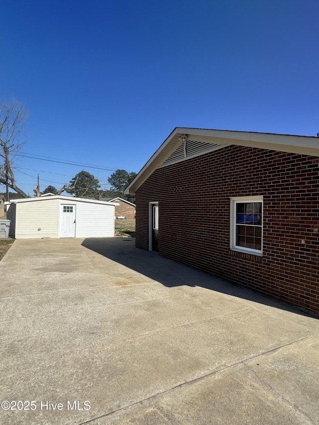 view of side of home with an outdoor structure and brick siding