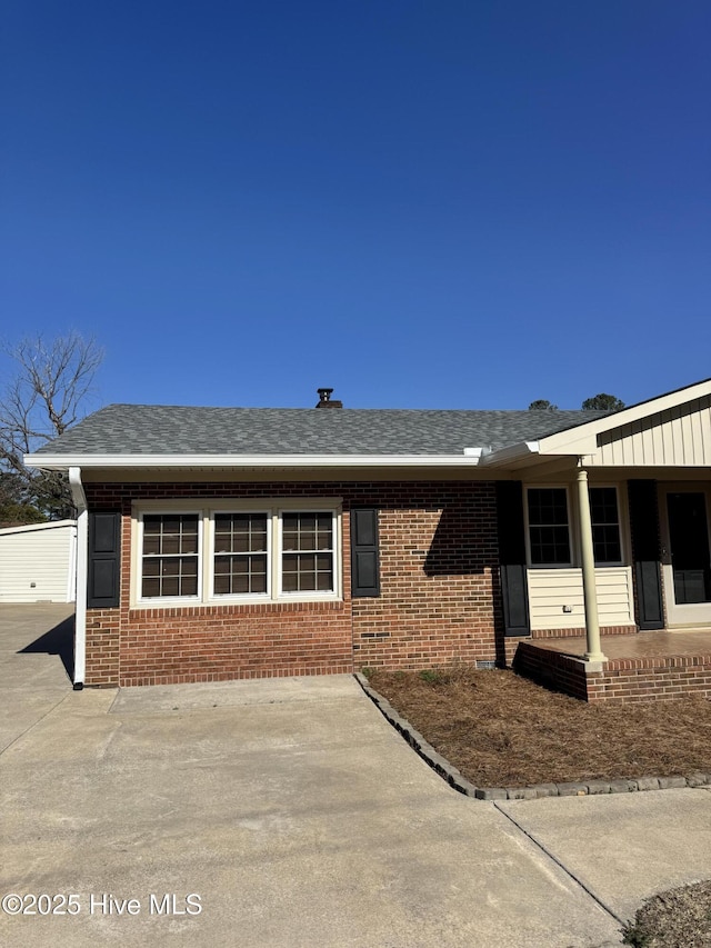 view of front of property with brick siding and roof with shingles