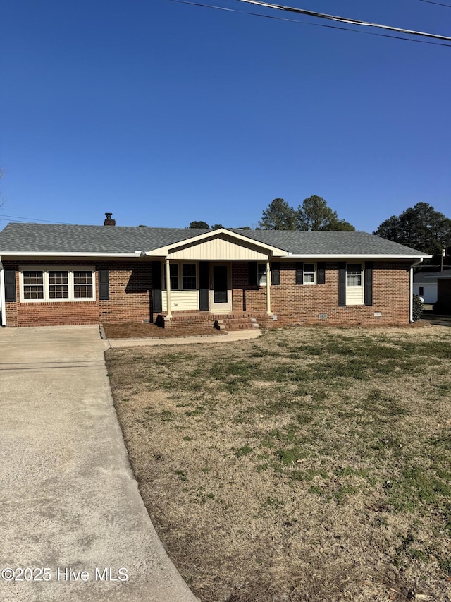 ranch-style house featuring a shingled roof, a front yard, and brick siding