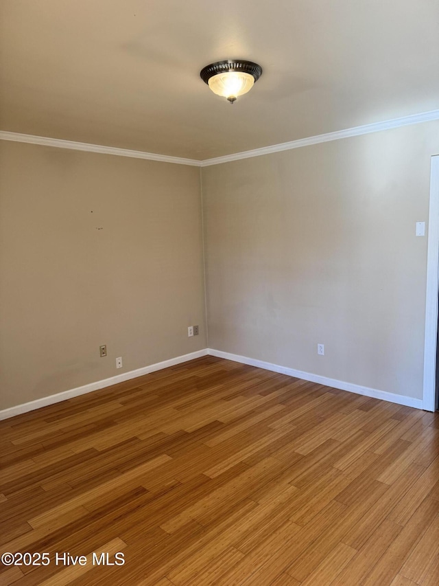 spare room with baseboards, light wood-style flooring, and crown molding