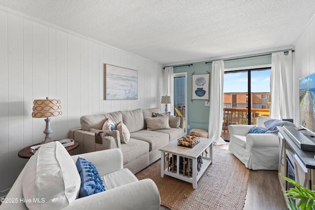 living area featuring a textured ceiling, ornamental molding, and wood finished floors