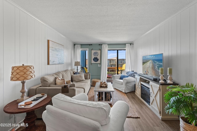 living area with ornamental molding, a textured ceiling, and wood finished floors