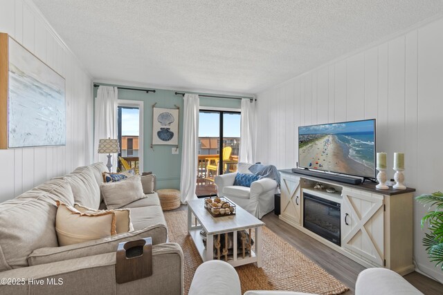 living area with crown molding, a textured ceiling, and wood finished floors