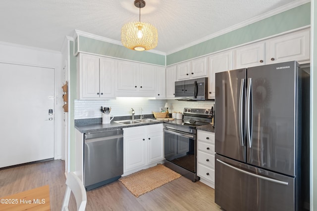 kitchen featuring white cabinets, dark countertops, appliances with stainless steel finishes, a sink, and light wood-type flooring