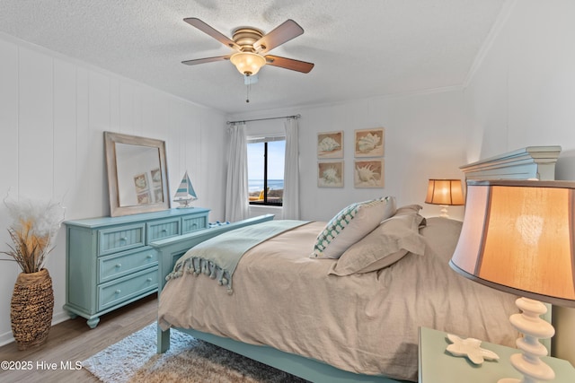 bedroom with a ceiling fan, a textured ceiling, and wood finished floors