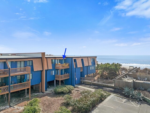 view of property with a water view, uncovered parking, and fence