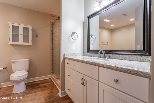 bathroom featuring visible vents, toilet, vanity, a shower stall, and wood finished floors