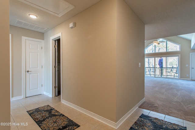 corridor with light carpet, visible vents, baseboards, lofted ceiling, and light tile patterned flooring