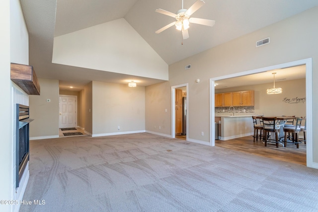 unfurnished living room with light carpet, ceiling fan, visible vents, and baseboards