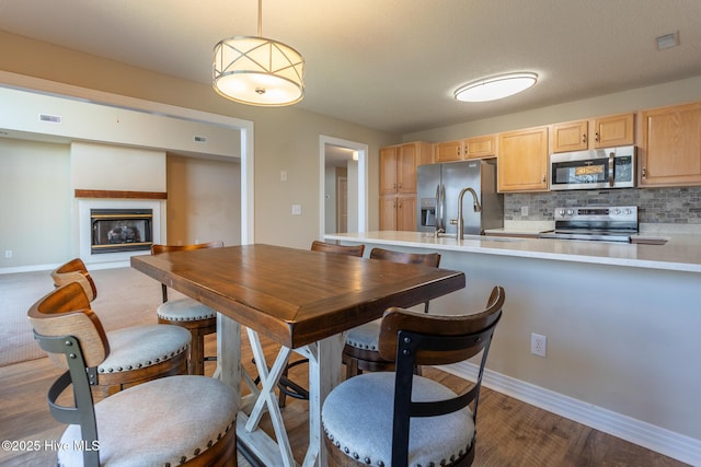 dining area featuring a glass covered fireplace, dark wood-style flooring, visible vents, and baseboards