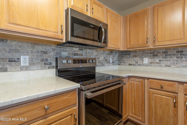 kitchen with tasteful backsplash, a textured ceiling, stainless steel appliances, and wood finished floors