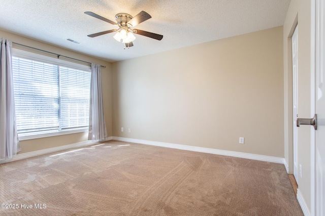 empty room with a textured ceiling, baseboards, visible vents, and light colored carpet