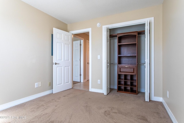 unfurnished bedroom featuring a closet, baseboards, and carpet flooring