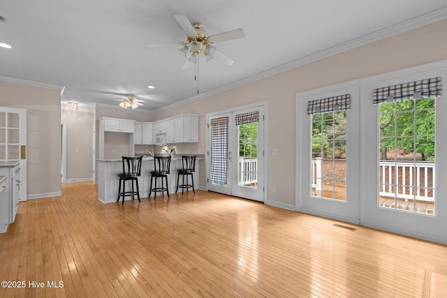 10 Lodge Pole Ln, Pinehurst, NC 28374 - kitchen featuring a ceiling fan, ornamental molding, white cabinetry, white microwave, and a kitchen bar