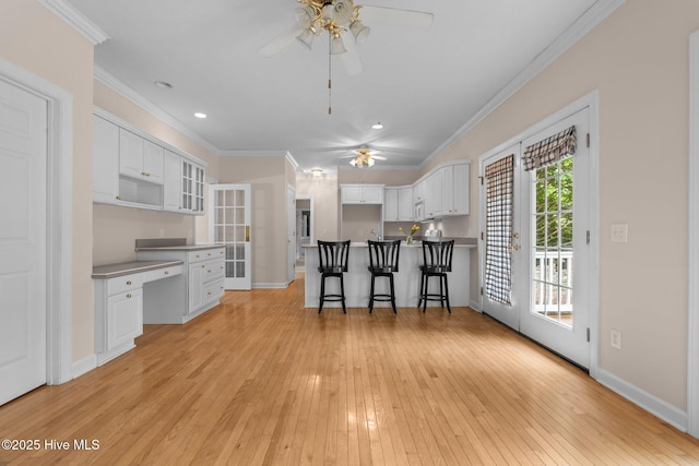 10 Lodge Pole Ln, Pinehurst, NC 28374 - kitchen featuring a ceiling fan, light wood-style floors, a peninsula, white cabinetry, and a kitchen bar
