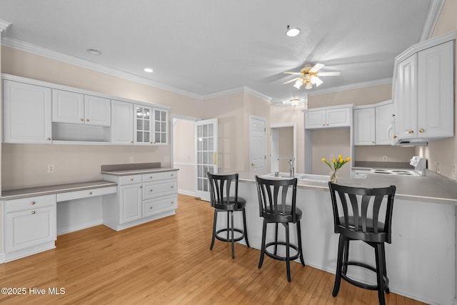 10 Lodge Pole Ln, Pinehurst, NC 28374 - kitchen featuring a peninsula, stove, a ceiling fan, white cabinets, and crown molding