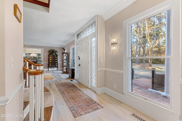 entryway featuring baseboards, visible vents, light wood-style flooring, stairs, and crown molding