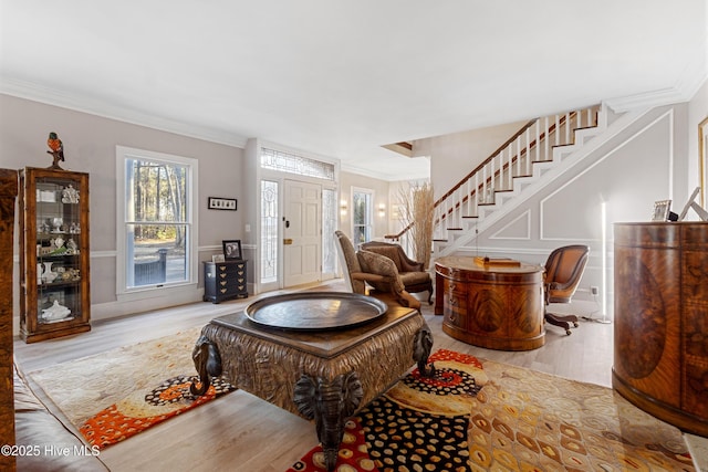 entryway with stairs, ornamental molding, wood finished floors, and a decorative wall