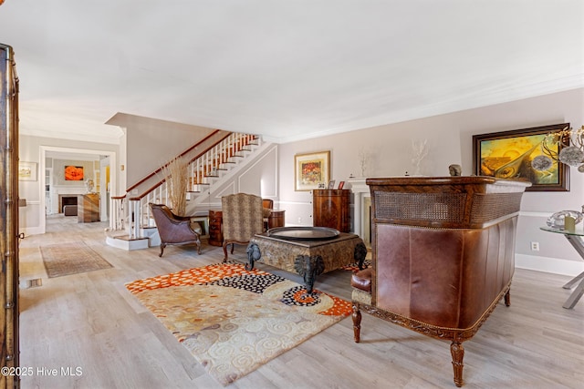 sitting room with stairs, ornamental molding, and wood finished floors