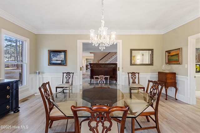 dining area featuring a chandelier, a wainscoted wall, light wood-style floors, and stairway