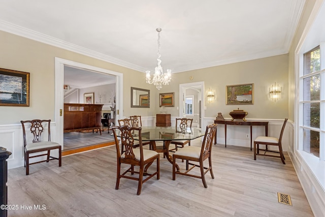 dining space featuring light wood-style floors, visible vents, and crown molding