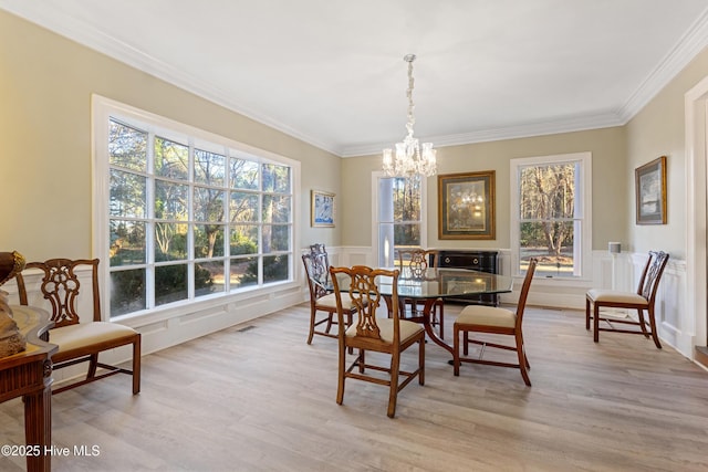 dining area featuring ornamental molding, wainscoting, light wood-style flooring, and visible vents