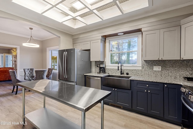 kitchen featuring light stone counters, backsplash, appliances with stainless steel finishes, a sink, and coffered ceiling