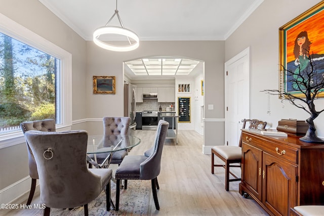 dining area featuring light wood-style flooring, baseboards, and crown molding