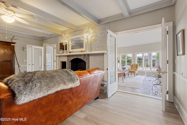 living area featuring french doors, a fireplace, ceiling fan, wood finished floors, and beamed ceiling